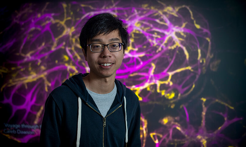 Dr Raymond Yip standing in front of scientific image