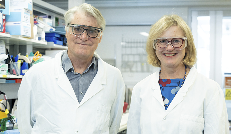 Professor Phil Hodgkin (left) and Professor Jo Douglass (right) both wearing white lab coats and safety goggles
