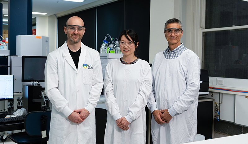 Associate Professor Andrew Webb, Associate Professor Cherie Chiang, and Dr Mustafa Ayhan are photographed in a laboratory, wearing white lab gowns and coats